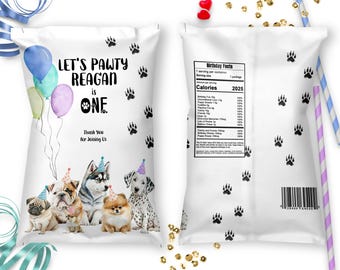 May include: White favor bag with a paw print design. The bag has a birthday message that says "Let's Pawty Reagan is One". The bag also has a thank you message and a picture of dogs wearing party hats.