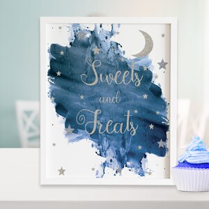 May include: A white framed sign with a blue watercolor background and silver glitter stars and a crescent moon. The sign says "Sweets and Treats" in silver glitter lettering.