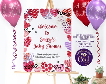 May include: Welcome to Emily's Baby Shower sign with a watercolor heart border. The sign is on an easel with pink and purple balloons. The text on the sign reads "Welcome to Emily's Baby Shower" and "Thank you for joining us! Saturday, February 11th, 202X".