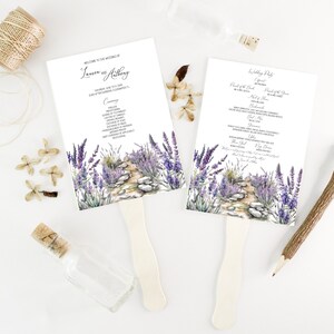 May include: Lavender wedding ceremony program fans with a watercolor illustration of a stone path lined with lavender flowers. The program includes the names "Lauren and Anthony" and the wedding date.