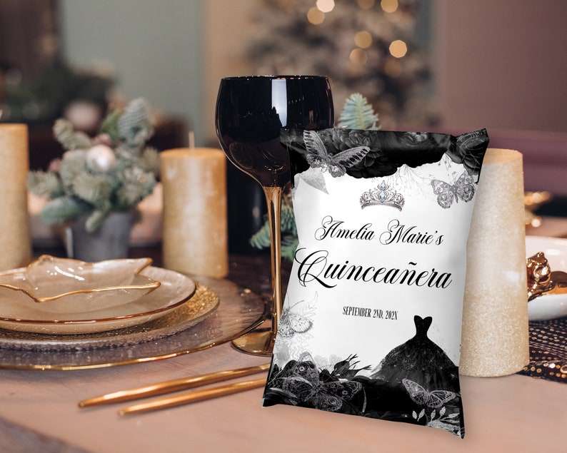 May include: A white cushion with black and silver accents features a butterfly design and the text "Amelia Marie's Quincea&ntilde;era September 24th, 2023".