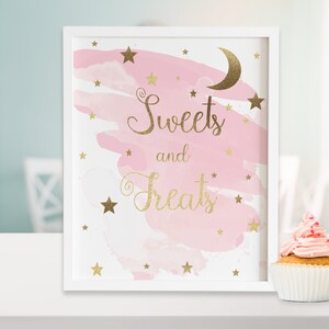 May include: A white framed sign with a pink watercolor background and gold glitter stars and a crescent moon. The sign says "Sweets and Treats" in gold glitter lettering.