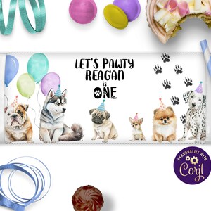 Op de afbeelding: Een rechthoekige banner met de tekst "LET'S PAWTY REAGAN is ONE" en illustraties van honden met feesthoeden. Ballonnen en pootafdrukken versieren de banner. Kleurrijke linten en snoepjes zijn ook zichtbaar.