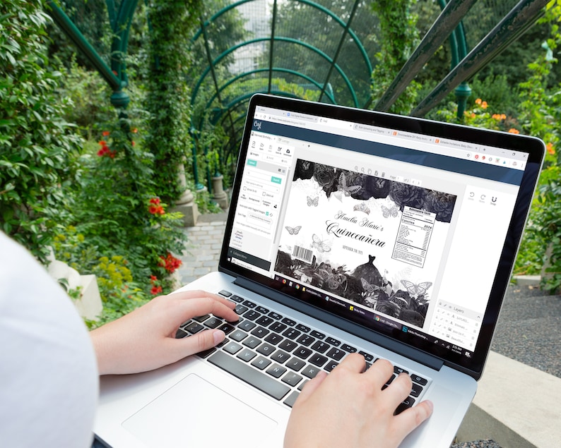 May include: A person using a laptop to design a label for a Quincea&ntilde;era celebration. The label features a black and white design with butterflies and the text "Amelia Marie's Quincea&ntilde;era".