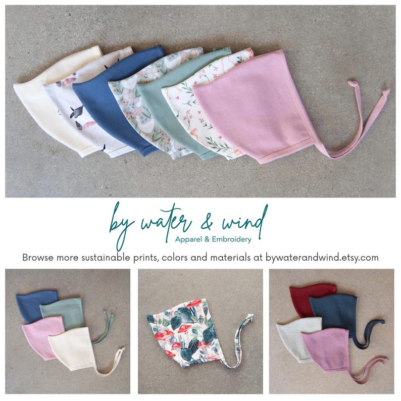May include: A collection of baby bonnets in various colors and patterns, including solid pink, blue, and floral prints. The bonnets are arranged in a row, showcasing the variety of designs. The text "by water & wind" is also visible.