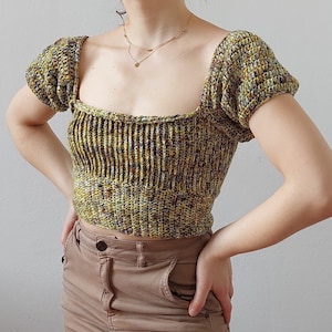 May include: A green and yellow crocheted crop top with a square neckline and puffed sleeves.