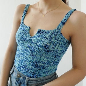 May include: A blue and green crochet tank top with a V-neckline. The top is made with a textured stitch and has a relaxed fit.