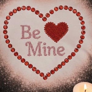 May include: A Valentine's Day design featuring a heart shape outlined with red gems. Inside the heart are the words "Be Mine" in pink glitter. A smaller heart is filled with red glitter. A lit candle is in the bottom right corner.