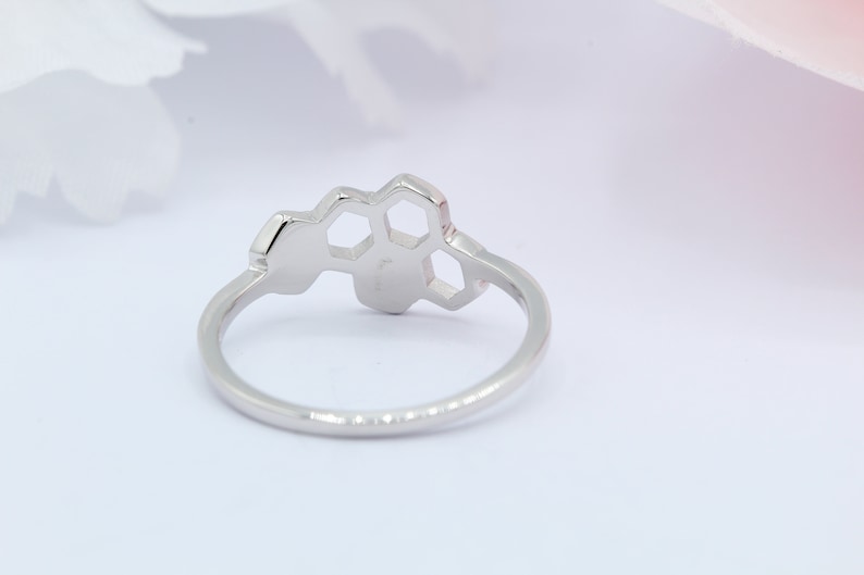 May include: A silver ring featuring a honeycomb design. The ring is simple and elegant.