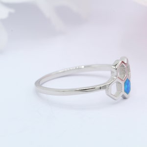 May include: A silver ring featuring a blue opal stone set within a honeycomb design.