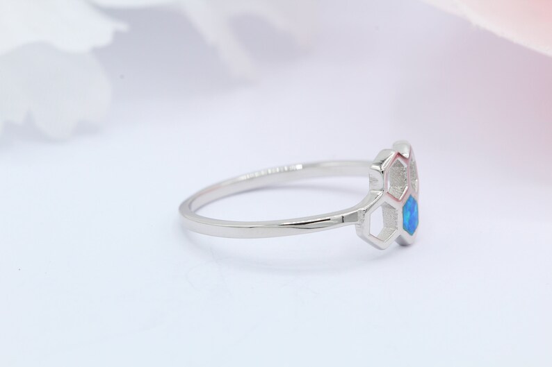 May include: A silver ring featuring a blue opal stone set within a honeycomb design.