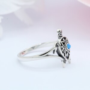 May include: A silver ring with a detailed turtle design and a blue opal gemstone. The ring is open and has a delicate band.