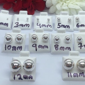 May include: A set of 10 pairs of sterling silver ball stud earrings in various sizes, ranging from 2mm to 12mm. The earrings are displayed on white cards with the size printed on each card.