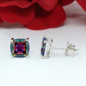 May include: A pair of silver stud earrings with a square-shaped, iridescent gemstone in the center of each earring.