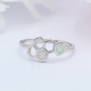 May include: A silver ring with a honeycomb design featuring three white opals.