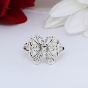 May include: A silver butterfly ring with an intricate design. The ring is made of sterling silver and has a delicate, feminine look.