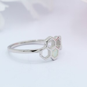 May include: A silver ring with a honeycomb design featuring white opal stones.