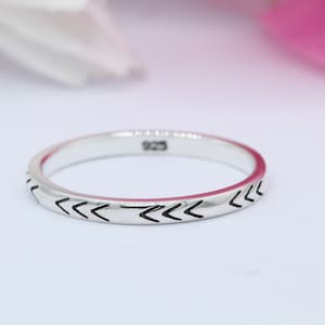 May include: A silver ring with a chevron pattern engraved around the band. The ring is marked with "925" on the inside.