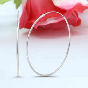May include: A pair of silver hoop earrings. The earrings are simple and elegant, with a smooth, polished finish.