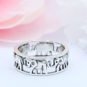 May include: A silver ring with a design of elephants walking around the band.