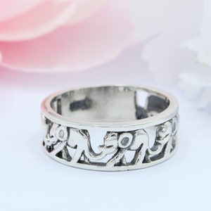 May include: A silver ring with a design of elephants walking around the band.