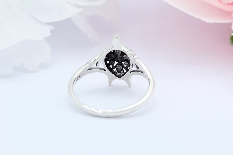 May include: A silver ring with a detailed turtle design. The turtle's shell is openwork and the ring is polished.