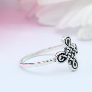 May include: A silver ring with a Celtic knot design. The knot is a four-leaf clover shape.
