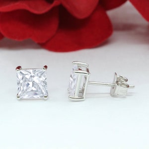 May include: A pair of silver square-shaped stud earrings with clear cubic zirconia stones.