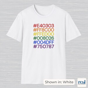 Op de afbeelding: Wit t-shirt met een regenboogkleurenpalet en bijbehorende hexadecimale kleurcodes. De kleuren zijn rood, oranje, geel, groen, blauw en paars. De tekst "Shown in: White" staat onderaan.