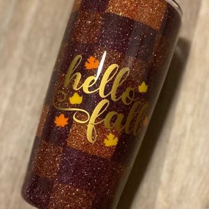 K&ouml;nnte beinhalten: Ein maronfarbener und goldfarbener Glitzerbecher mit einem karierten Muster. Der Becher tr&auml;gt die Aufschrift "hello fall" in goldfarbenem Glitzer mit kleinen goldfarbenen Glitzerblattakzenten.