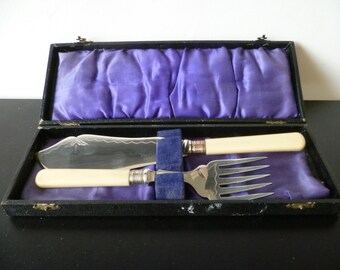 Una antigua cantimplora de cuero sintético con cubiertos para servir pescado con mango de hueso falso