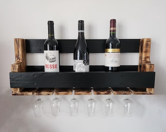 May include: Black wooden wine rack with three bottles of wine and six wine glasses. The bottles are labelled "ROSSO", "Viento", and "Vield de Noble".