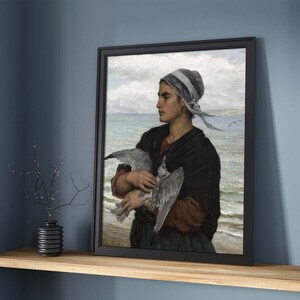 May include: A painting of a woman in a white cap holding a seagull in her arms. She is standing on a beach with the ocean in the background.
