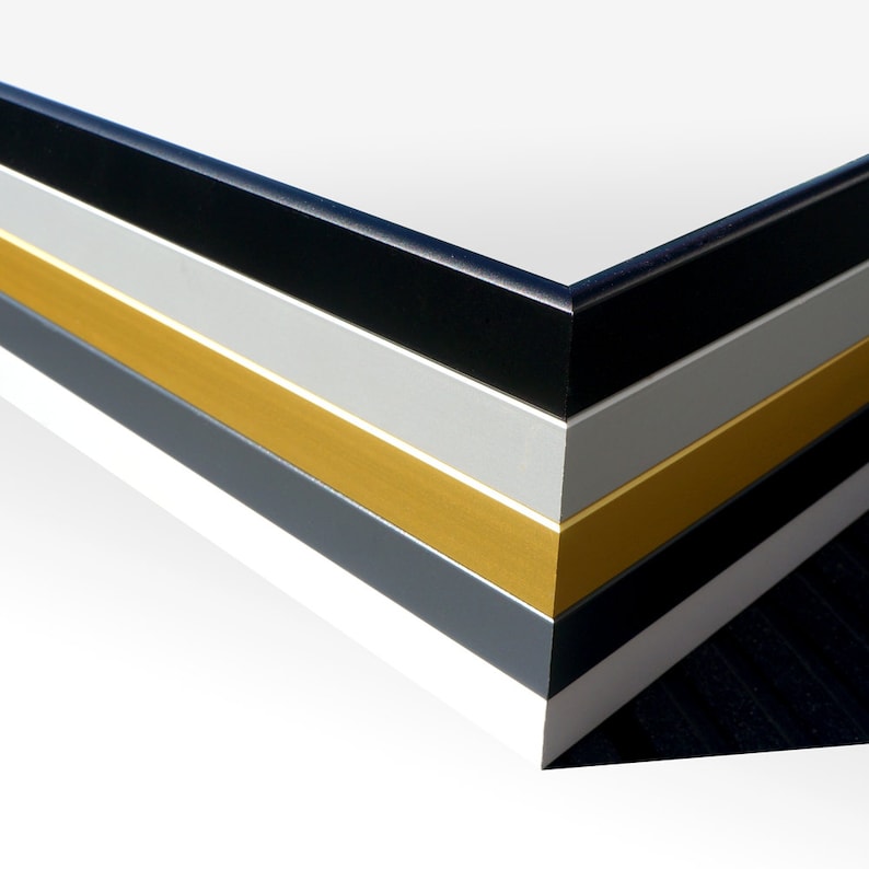 May include: Close-up of a corner of a picture frame with multiple layers of black, gray, gold, and white matting.
