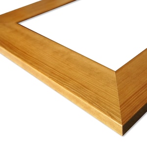 May include: Close-up of a corner of a natural wood picture frame. The frame is a light brown colour with a smooth finish.