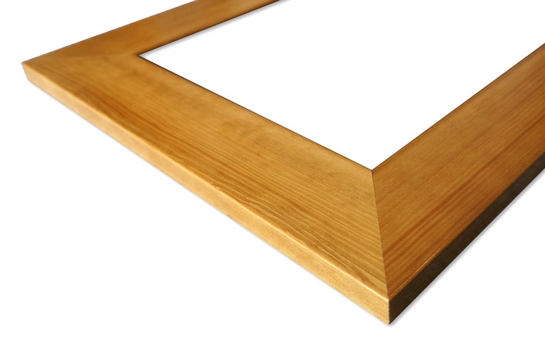 Puede incluir: Una esquina de un marco de fotos rectangular de madera. El marco es de madera marr&oacute;n claro con vetas visibles y un borde biselado. El marco est&aacute; vac&iacute;o, con un fondo blanco.
