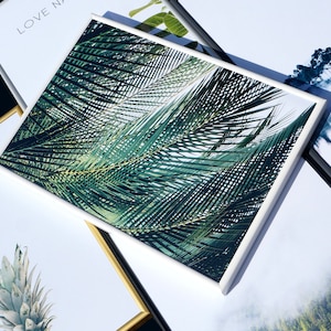 May include: Four framed prints with different nature scenes. The top print features a green leafy plant, the left print says "LOVE NATURE", the right print shows a foggy forest, and the bottom print shows a pineapple.