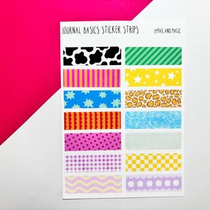 May include: A sheet of decorative sticker strips featuring diverse patterns such as cow print, stripes, stars, and polka dots. The text "JOURNAL BASICS STICKER STRIPS" and "@mail.and.magic" are printed on the sheet. The background is white and pink.