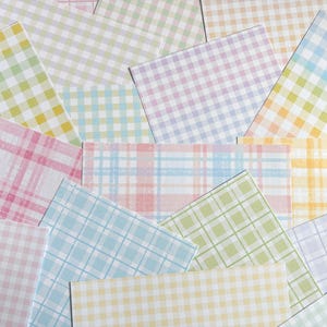 May include: A selection of pastel-coloured paper sheets featuring gingham and plaid patterns. The sheets are in shades of pink, yellow, blue, and green, creating a soft aesthetic. The arrangement is scattered, showcasing the variety of designs.