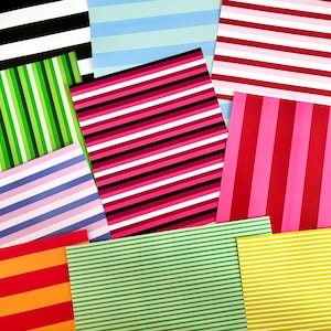 Op de afbeelding: Een verzameling kleurrijke gestreepte papieren in verschillende tinten, waaronder zwart en wit, groen, roze, rood en geel. De strepen variëren in breedte en richting, waardoor een visueel dynamische opstelling ontstaat. Ideaal voor knutselen of decoratieve doeleinden.