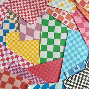 May include: A collection of rectangular paper sheets featuring various patterns including checkered grids in bright colours like green, yellow, blue, pink, and orange, alongside designs with small pink hearts, yellow stars, and pink starburst shapes.