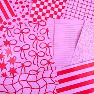 May include: An assortment of pink and red patterned papers. Designs include stripes, cherries, bows, stars, grids, and lined paper. The papers are arranged in an overlapping fashion, creating a vibrant and playful aesthetic.