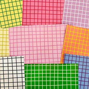 May include: A selection of fabric samples in a variety of colours, each with a grid pattern. The swatches include yellow, pink, green, blue, and orange. The grid lines are in contrasting colours, creating a visually appealing design.
