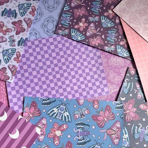 May include: A collection of patterned papers featuring various designs including moths in shades of pink, blue, and purple, a purple and light purple checkerboard pattern, a pink grid pattern, and a purple background with white crescent moons.