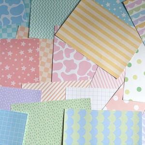 Peut inclure: Une collection de feuilles de papier rectangulaires présentant divers motifs pastel, notamment des taches de vache, des étoiles, des rayures, des pois, des grilles à carreaux et des vagues festonnées dans des tons rose, jaune, bleu, vert et lavande.