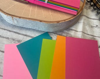 May include: Five sheets of cardstock in different colors: pink, teal, green, orange, and red. The sheets are stacked on top of each other.