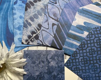 May include: A set of eight blue patterned envelopes with a white card and a blue pen. The envelopes have various blue patterns, including swirls, geometric shapes, and abstract designs.