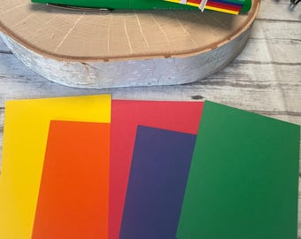 May include: Five blank cards in different colors: yellow, orange, red, blue, and green. The cards are arranged in a rainbow pattern.