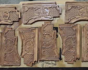 May include: A collection of eight rectangular wooden architectural corbels featuring intricate carved details, including central floral motifs and a cross-hatched grid pattern. Each piece displays a light brown wood grain finish with carved edges.