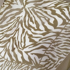 Puede incluir: Una tela de estampado de cebra blanco y marrón con una textura transparente. La tela está doblada por la mitad y el estampado es visible en ambos lados.